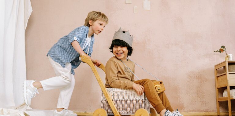 Dve deti hrajúce sa v detskom kočíku v izbe